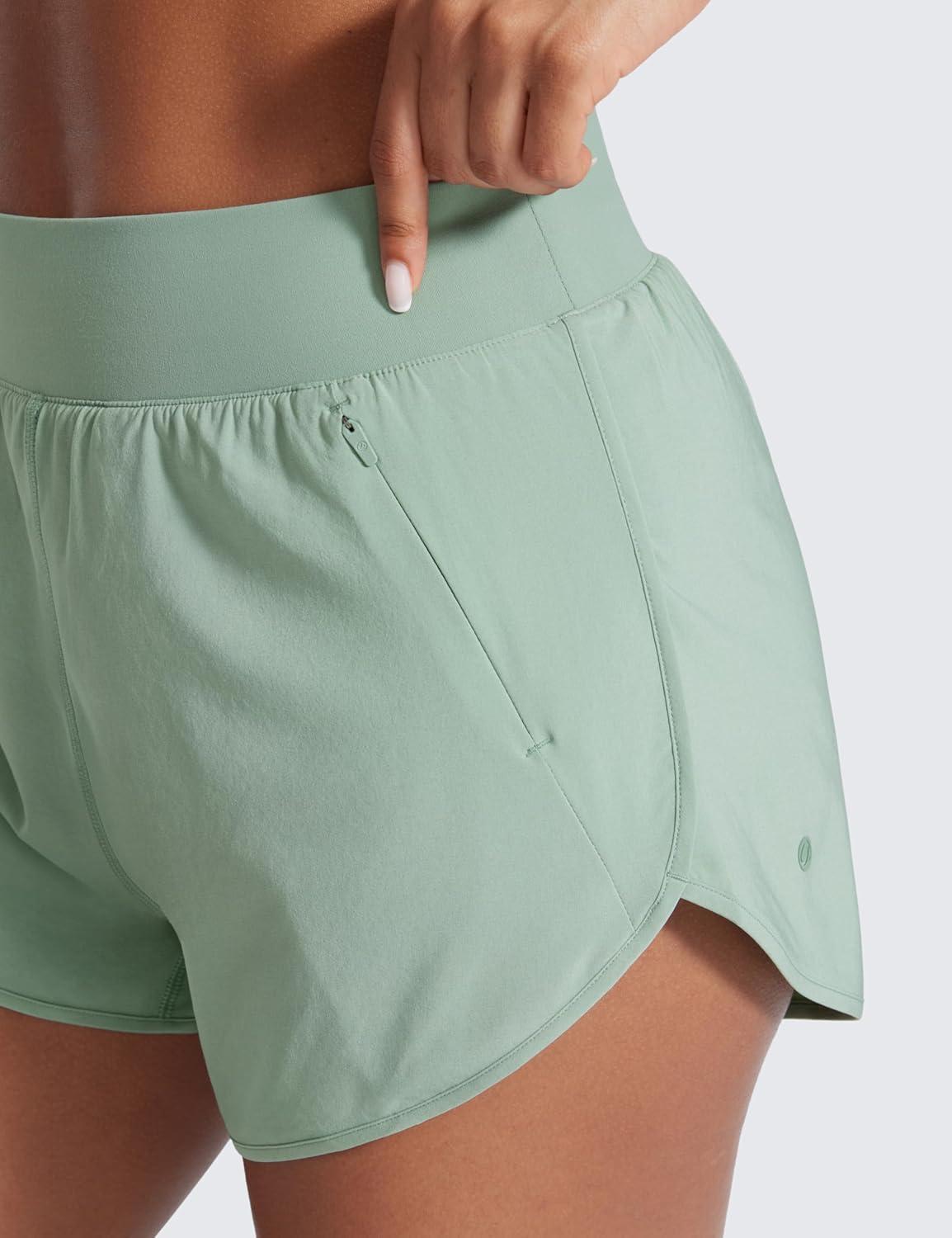 imageCRZ YOGA Dolphin Flat Waist Athletic Shorts for Women 3quot High Rise Quick Dry for Running Workout Gym Track with Zip PocketsGreen Palm Court